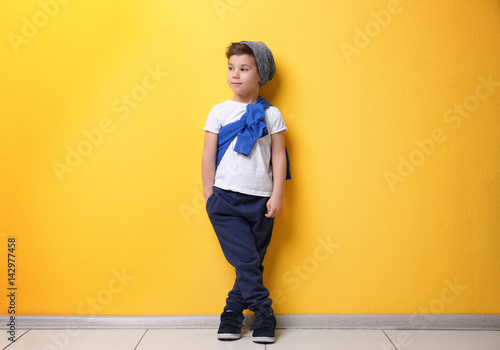Cute stylish boy near color wall