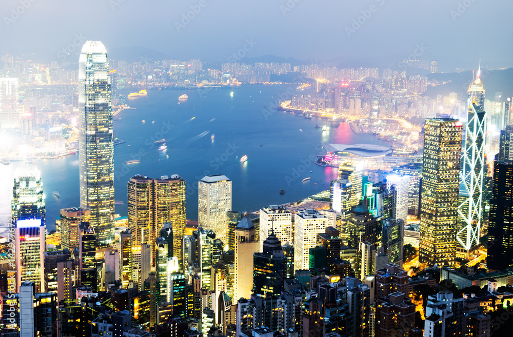Obraz premium Hong Kong cityscape at night with victoria harbour and large group of tall buildings.