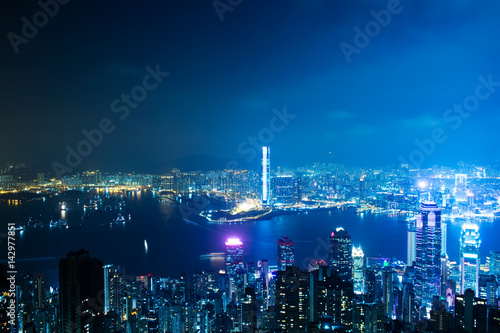 Hong Kong cityscape at night with victoria harbour and large group of tall buildings.