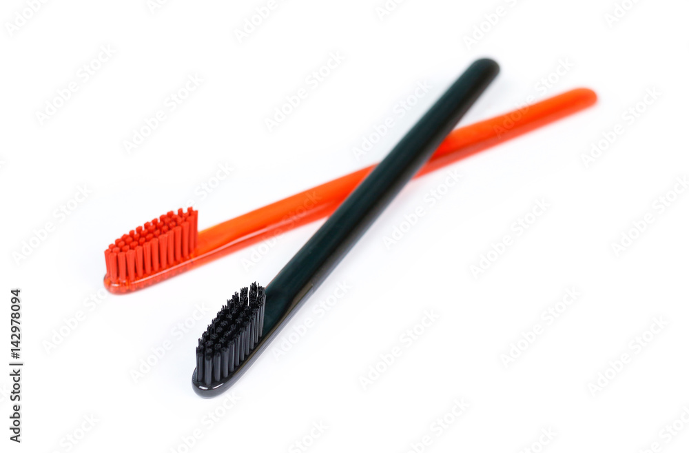 Closeup of two toothbrushes. For men and women. Full black and orange brush. Brush for the family. Isolated on a white background Closeup of two toothbrushes. For men and women. Full black and orange brush. Brush for the family. Isolated on a white background