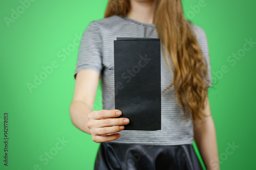 Woman showing blank black flyer paper. Leaflet presentation. Pamphlet hold hands. Girl show clear offset paper. Sheet template. Booklet design sheet display read first person