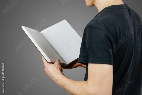 Closeup of guy in black t-shirt holding blank open white book on isolated grey background. Education concept. Mock up