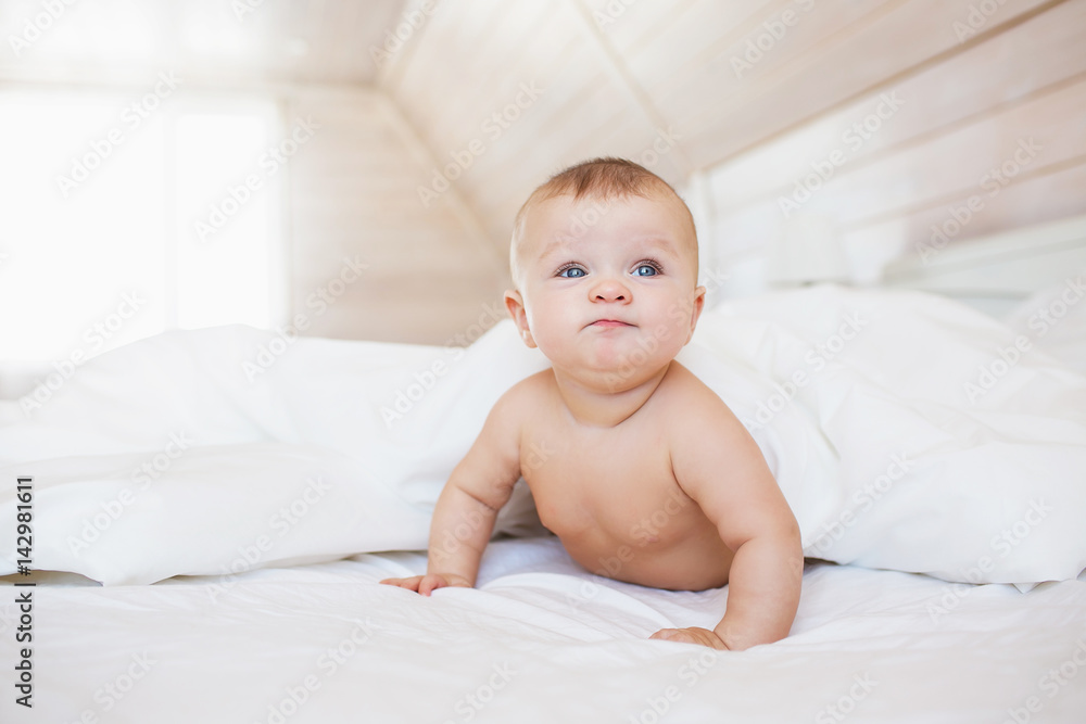 Angry and funny little baby lies on a white bed Angry and funny little baby lies on a white bed