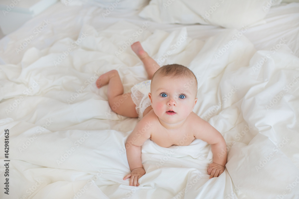 TOP VIEW: Infant on a white bed in bedroom TOP VIEW: Infant on a white bed in bedroom