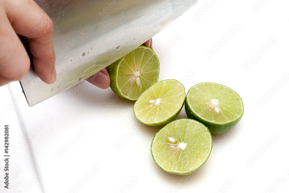 Slicing lime with knife on white cutting board