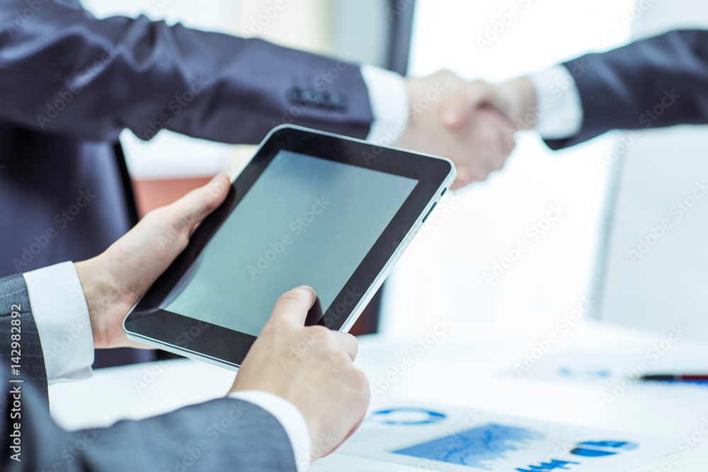 businessman with digital tablet on background of business partners handshaking businessman with digital tablet on background of business partners handshaking