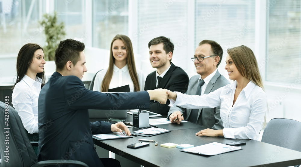 handshake business partners at a meeting in creative office on the background of business team handshake business partners at a meeting in creative office on the background of business team