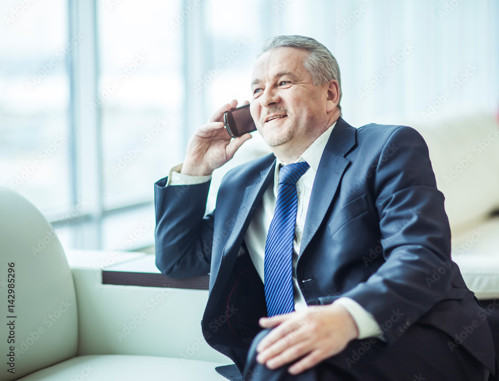 successful businessman talking on his smartphone sitting on couch in the office