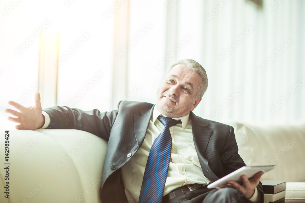 successful businessman with digital tablet sitting on the sofa in the private office successful businessman with digital tablet sitting on the sofa in the private office