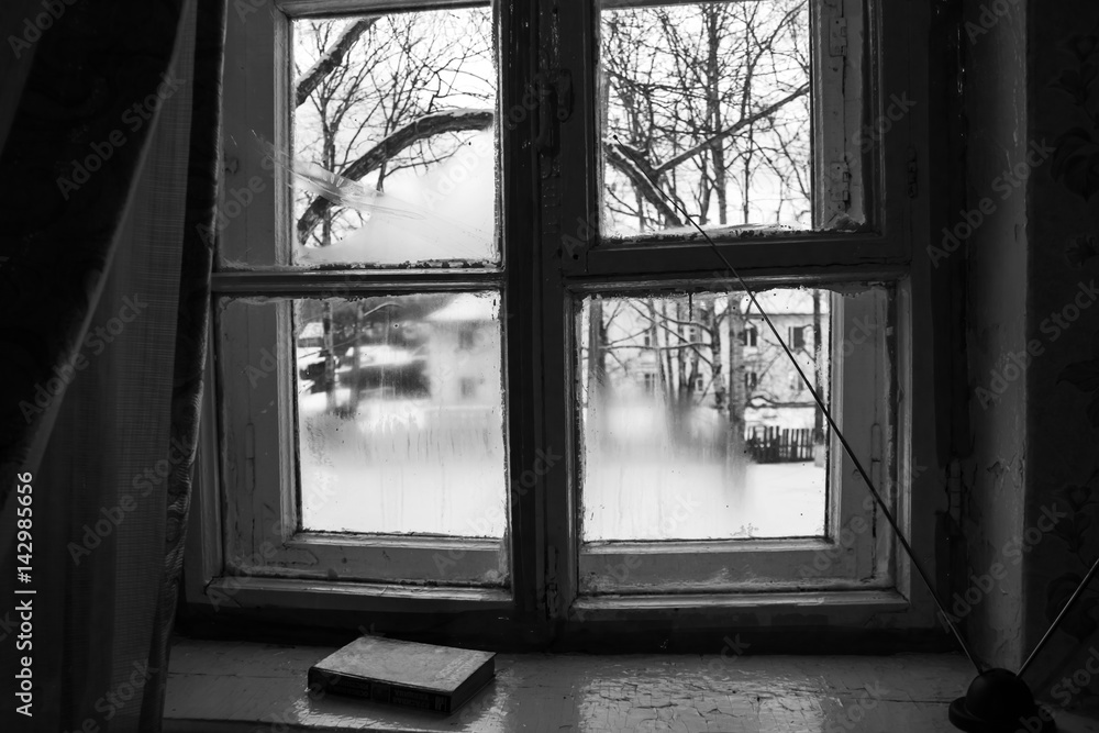 Fototapeta premium A wooden old window from which a winter courtyard is visible. Khabarovsk Krai settlement Vysokogorny March 2017