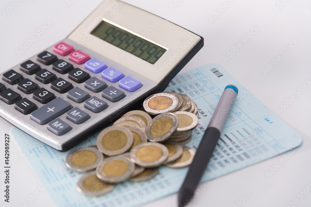 Increasing columns of coins, piles of coins arranged as a graph and calculator with pen on white background Increasing columns of coins, piles of coins arranged as a graph and calculator with pen on white background