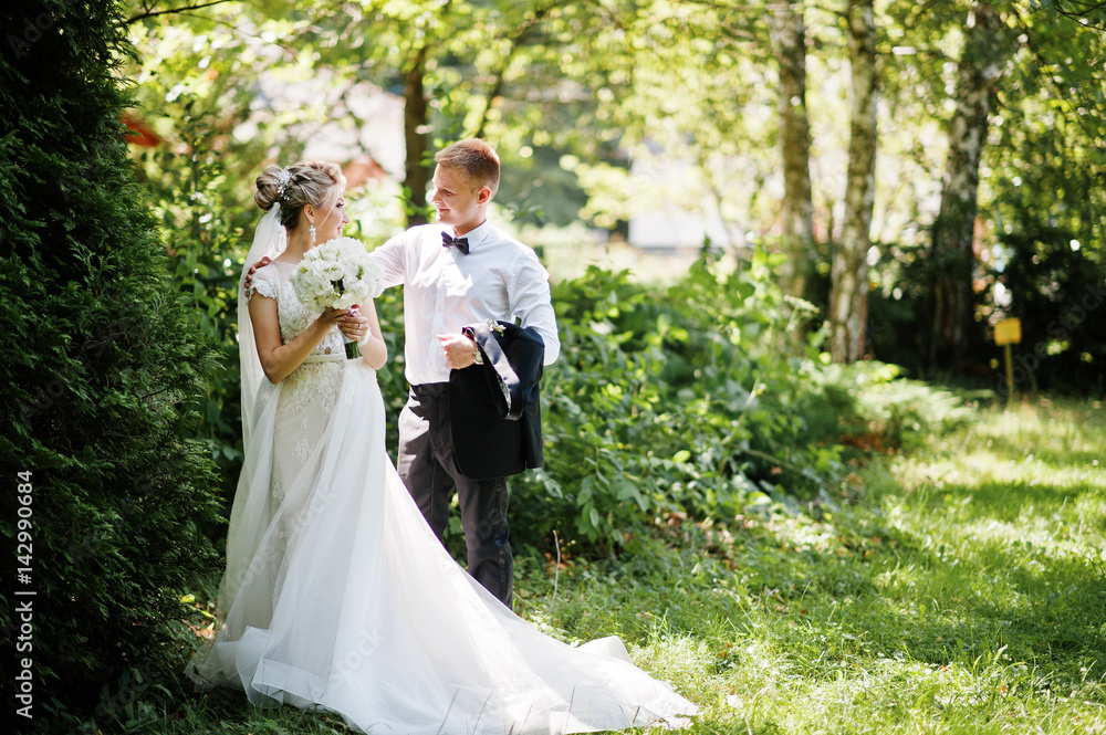 Stylish and gorgeous wedding couple walking outdoor at park on sunny weather.