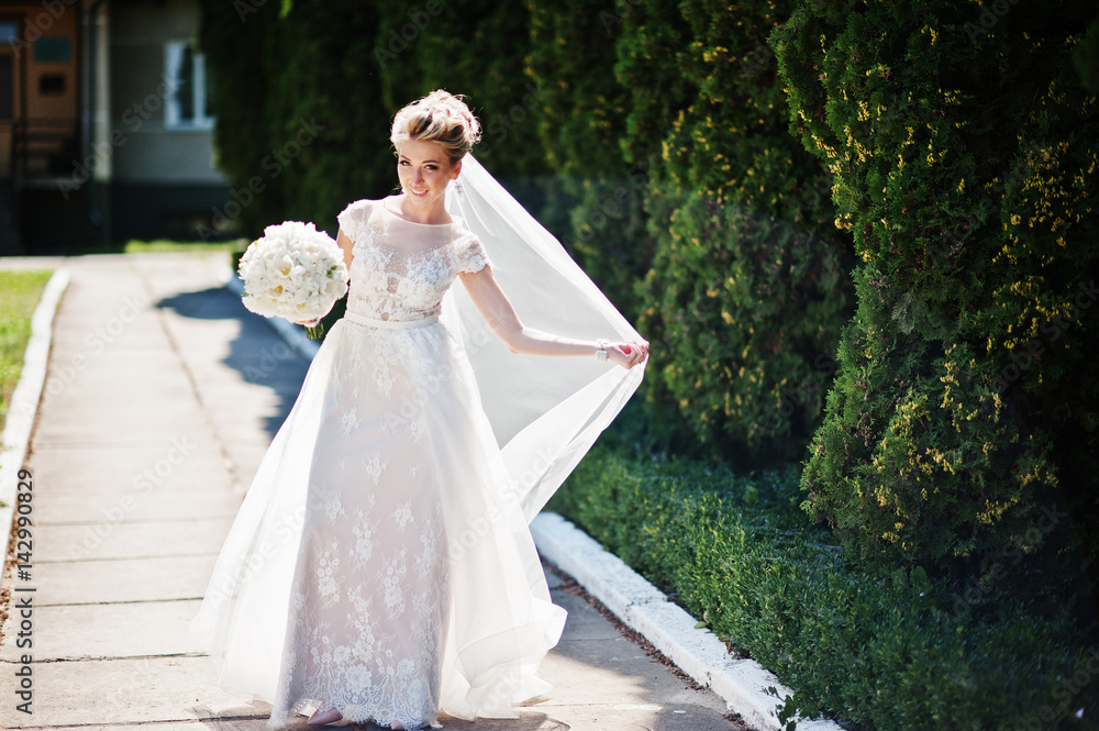 Fototapeta premium Awesome gorgeous blonde bride with wedding bouquet at hands at sunny day.