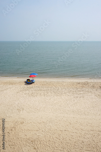 red and blue parasols with inflatable boat on the clear beach