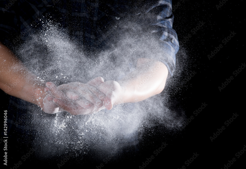 Chef hand clap with splash of white flour and black background