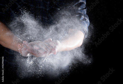 Chef hand clap with splash of white flour and black background © showcake