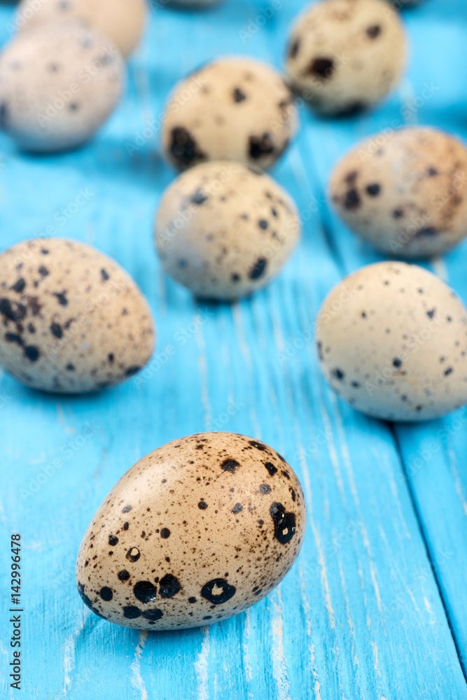 Scattered raw quail eggs on wooden background Scattered raw quail eggs on wooden background