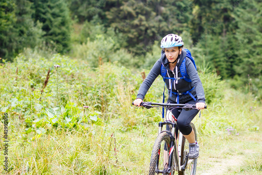 Young smiling woman Young woman riding bicycle in mountain forest on summer day Young smiling woman Young woman riding bicycle in mountain forest on summer day
