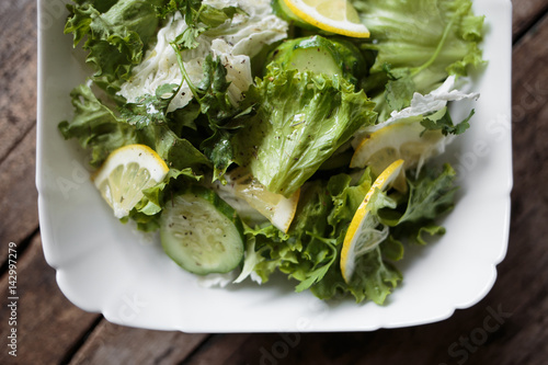 Fresh salad in white bowl on wooden background. Close up image of healthy food