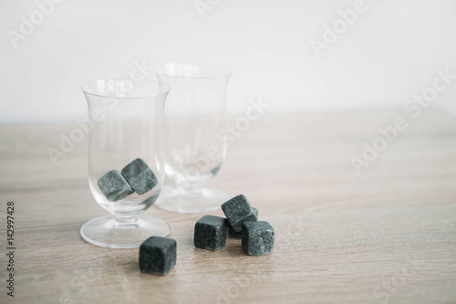 Stones for cooling whiskey and glases tulup on light wooden background photo