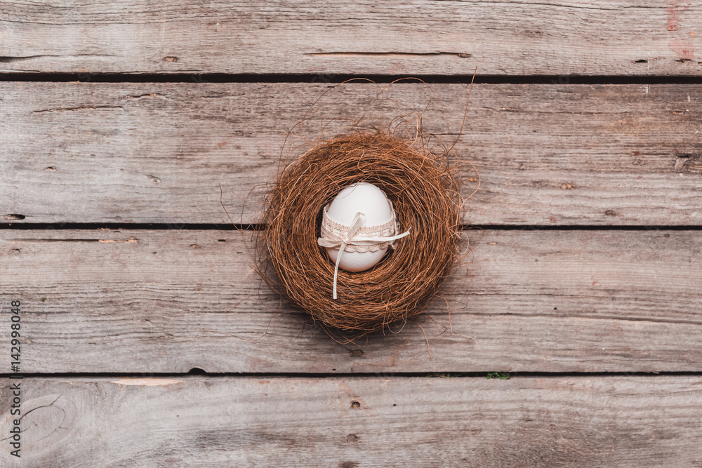 top view of easter egg with ribbon in nest on wooden tabletop. Happy Easter concept top view of easter egg with ribbon in nest on wooden tabletop. Happy Easter concept
