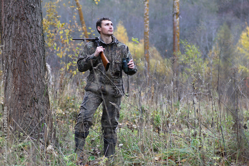 Man in camouflage and with guns in a forest belt on a spring hun