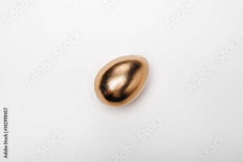 Close-up top view of golden Easter egg on white background, Happy Easter concept