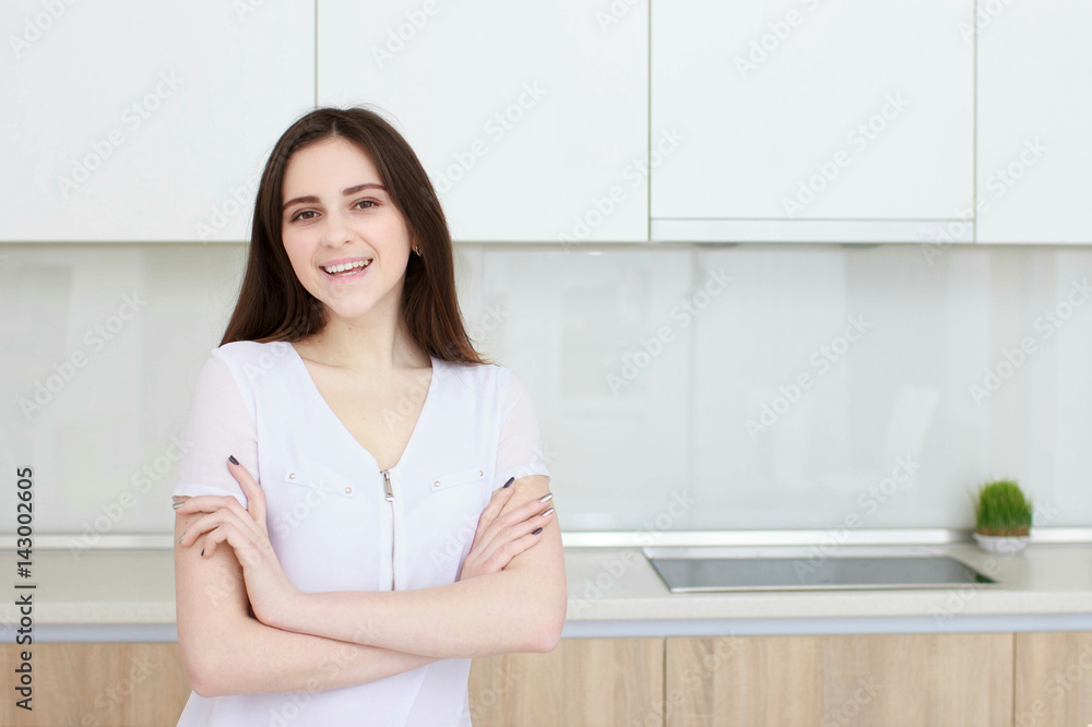 Pretty young woman With black hair standing in kitchen and smiling Pretty young woman With black hair standing in kitchen and smiling