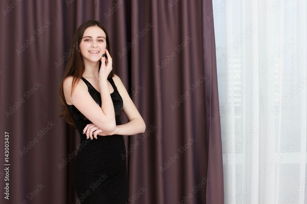Young girl with black dress against curtains. Looking at the camera Young girl with black dress against curtains. Looking at the camera
