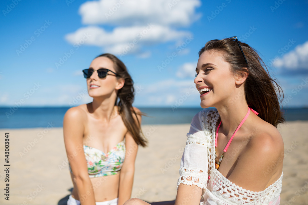 Beautiful young woman sunbathing with friend laughing