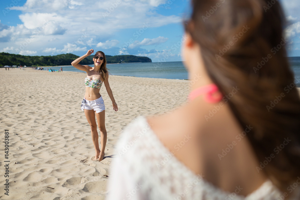 Happy girl standing on beach smiling to her friend Happy girl standing on beach smiling to her friend