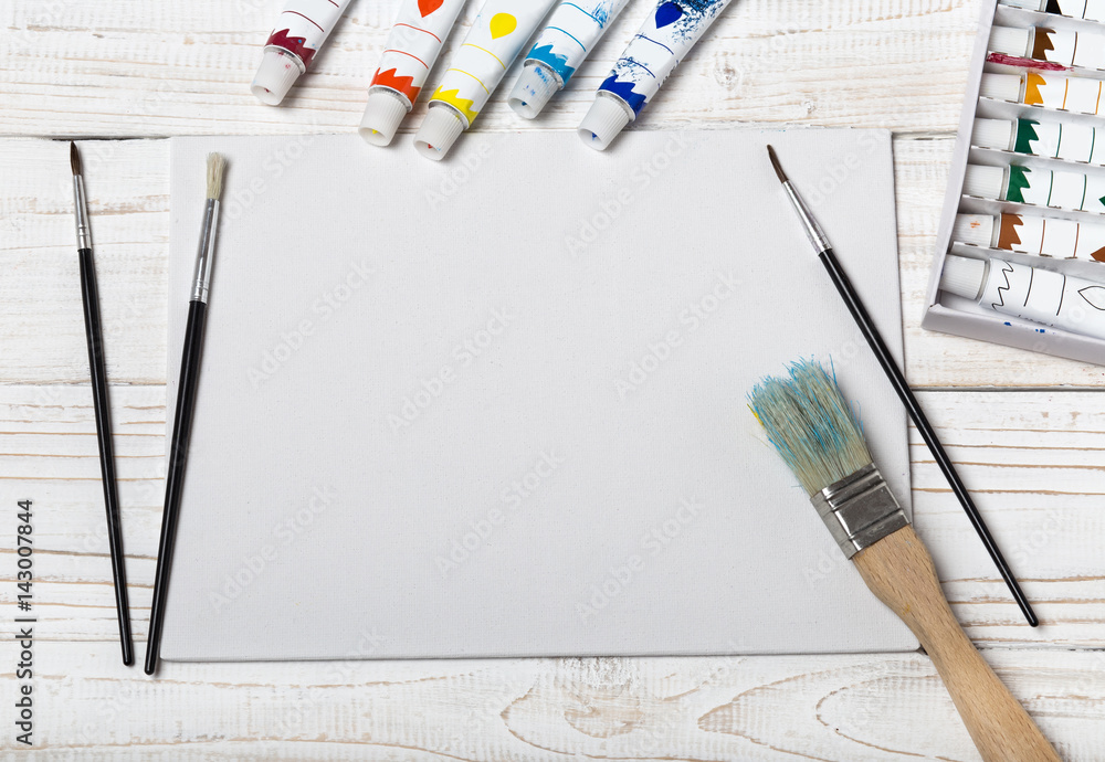 Artist's workshop. Canvas, paint, brushes, palette knife lying on the  table.Art tools.Artist workplace background.Acrylic paint and brushes.Art  picture with copy space and for add text. Stock Photo