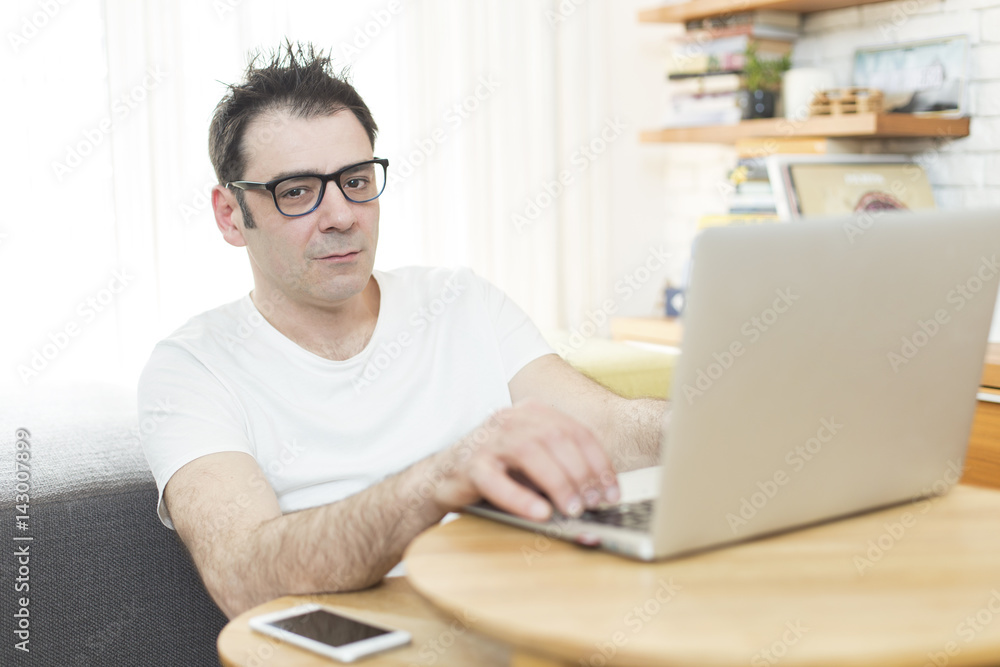 Man sitting in his living room and working on laptop. Morning scene Man sitting in his living room and working on laptop. Morning scene
