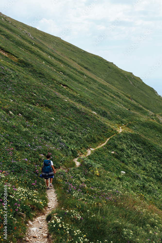A lonely adventurer hikes through the narrow mountain path trail while travelling on his own through georgia A lonely adventurer hikes through the narrow mountain path trail while travelling on his own through georgia