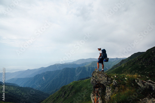 Young teenager looks at the view on a holiday hiking trip backpacking through the mountains and camping long trails happiness active fitness sunlight beautiful © onewithahalf