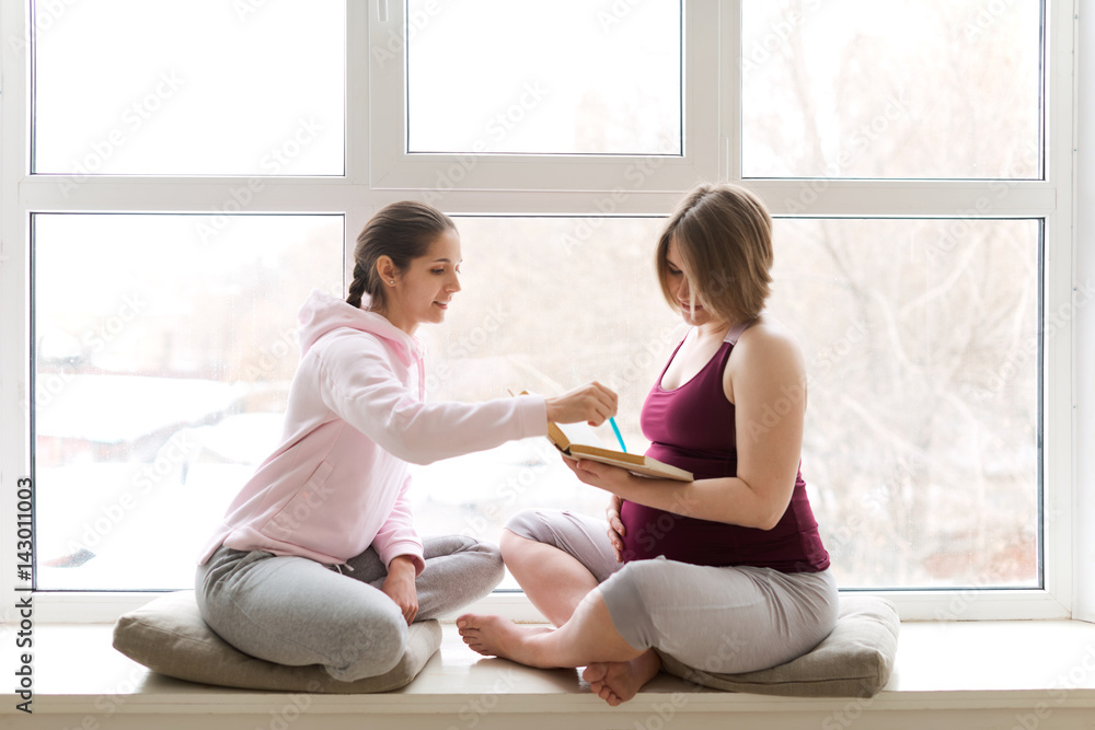 Personal trainer giving advice to pregnant woman on exercises