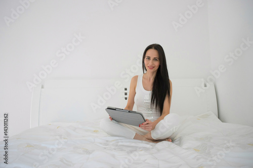 A woman lies on her bed using her tablet