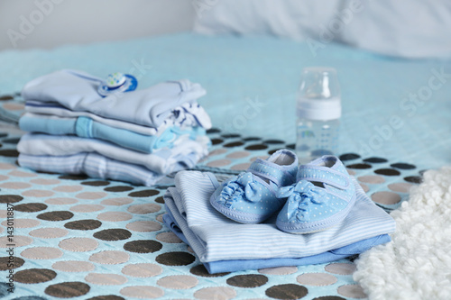 Pile of baby clothes on bed photo