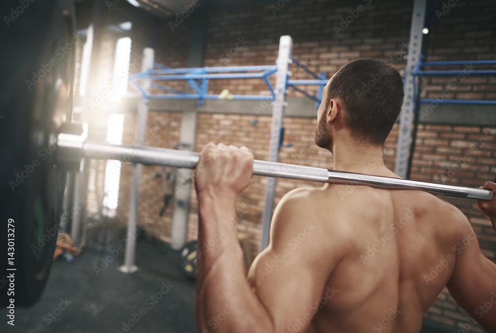 Naklejka premium Rear view of man with a barbell