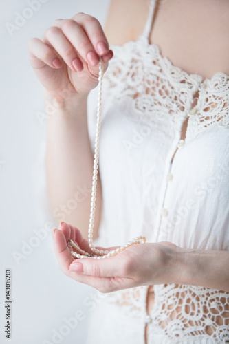 photo of young woman holding pearl necklace on the wonderful white background