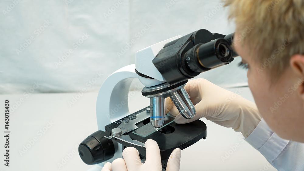 Female doctor scientist lab researcher looking through the microscope. Closeup shot of medical examination process.