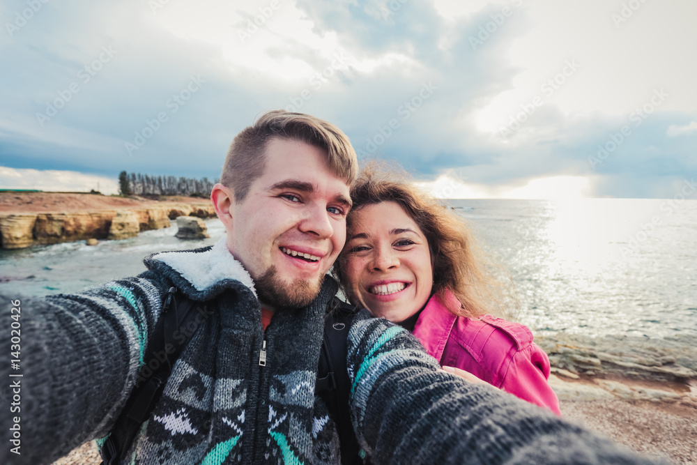 Young happy couple is taking selfie photo on vacation near sea.