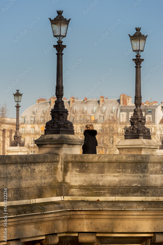 Young woman waits for her date near the street lamps of Paris