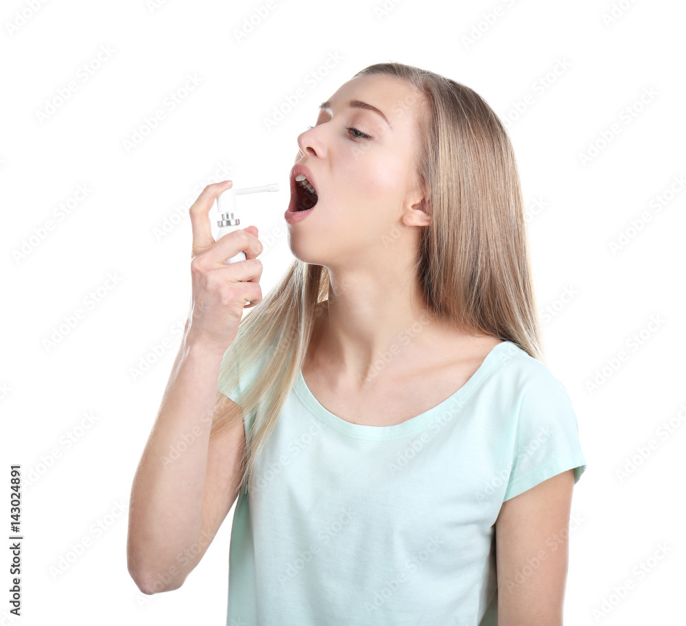 Sick young woman using throat spray on white background Sick young woman using throat spray on white background