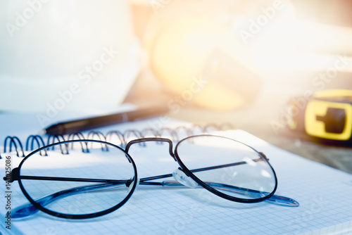 Engineers placed the spectacles on diary after work with sunlight. Go to relaxing in the weekend activity concept.