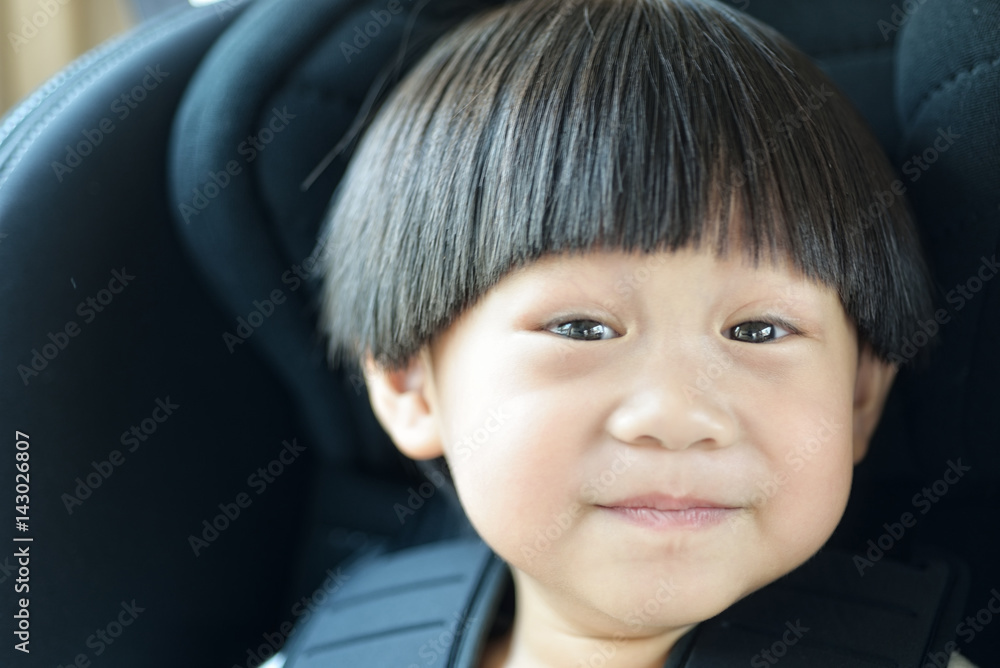Obraz premium Portrait happy toddler boy sitting in the car seat : Soft focus