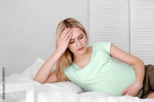 Young pregnant woman suffering from headache at home