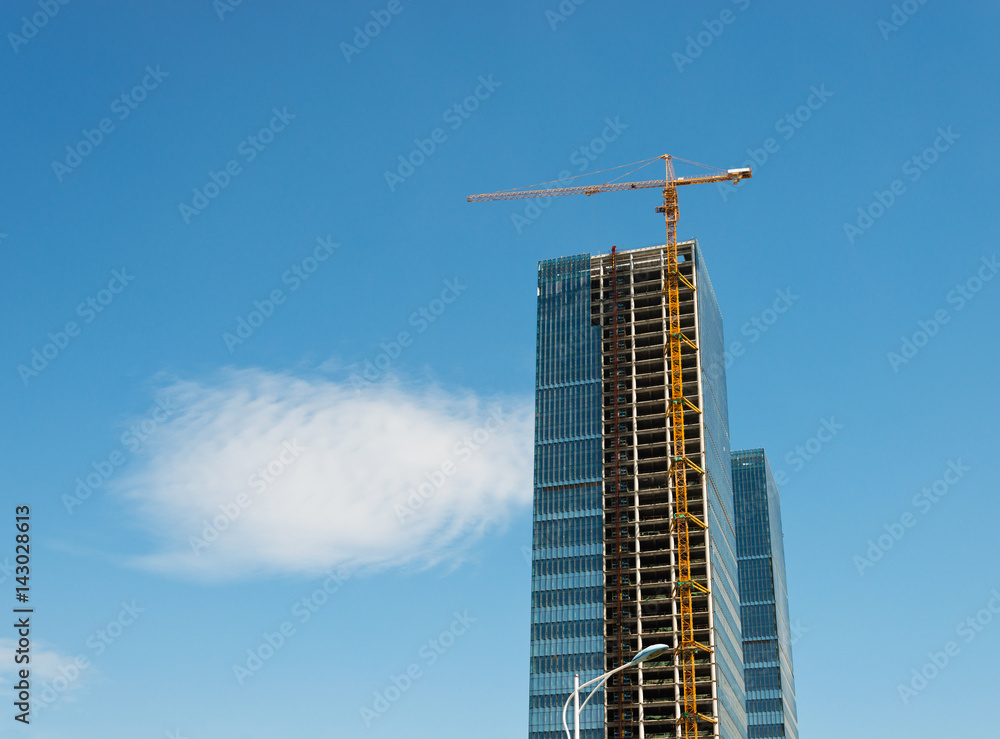 Construction site with cranes on blue sky background.