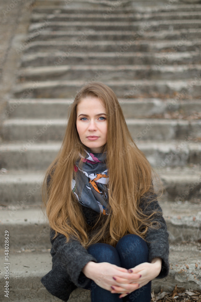 Portrait of a beautiful girl in early spring on the steps Portrait of a beautiful girl in early spring on the steps