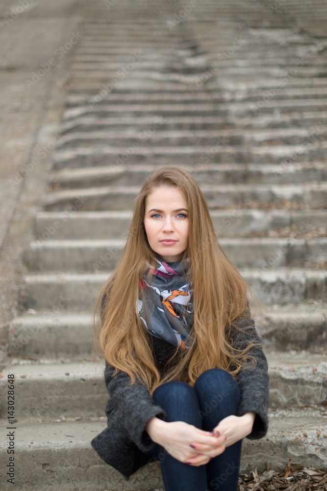 Portrait of a beautiful girl in early spring on the steps Portrait of a beautiful girl in early spring on the steps